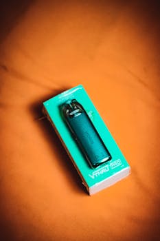 Stylish electronic vape device packaged in a box, set against a striking orange backdrop, showcasing modern lifestyle tech.
