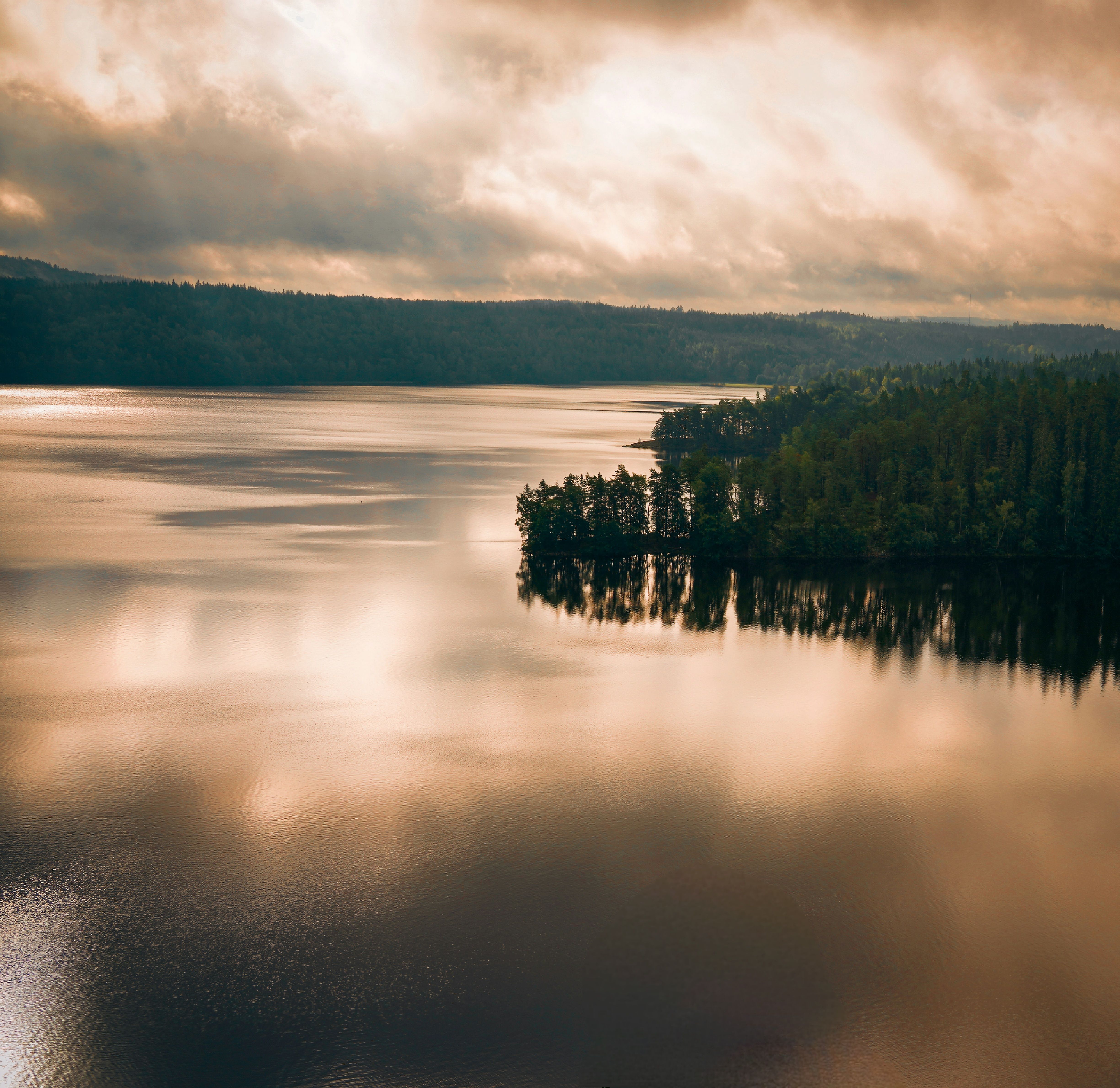 Ruhiger See mit Wald und Wolken