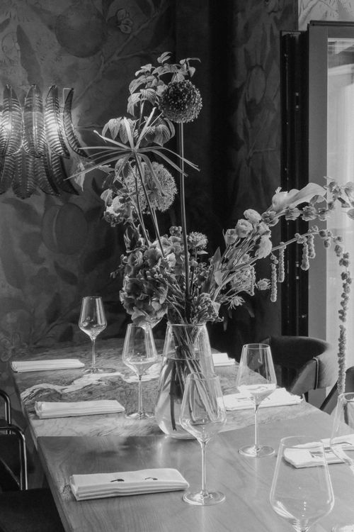 Free Black and white photo of a table setting with a floral arrangement, glassware, and napkins. Stock Photo