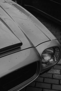 Close-up of a vintage car hood with rain droplets, evoking nostalgia.