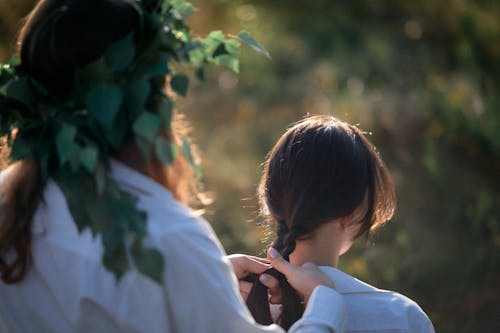 Woman is Braiding Hair of Friend in Nature