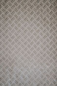 Close-up of a diamond plate pattern on a textured metal surface, showcasing industrial design.