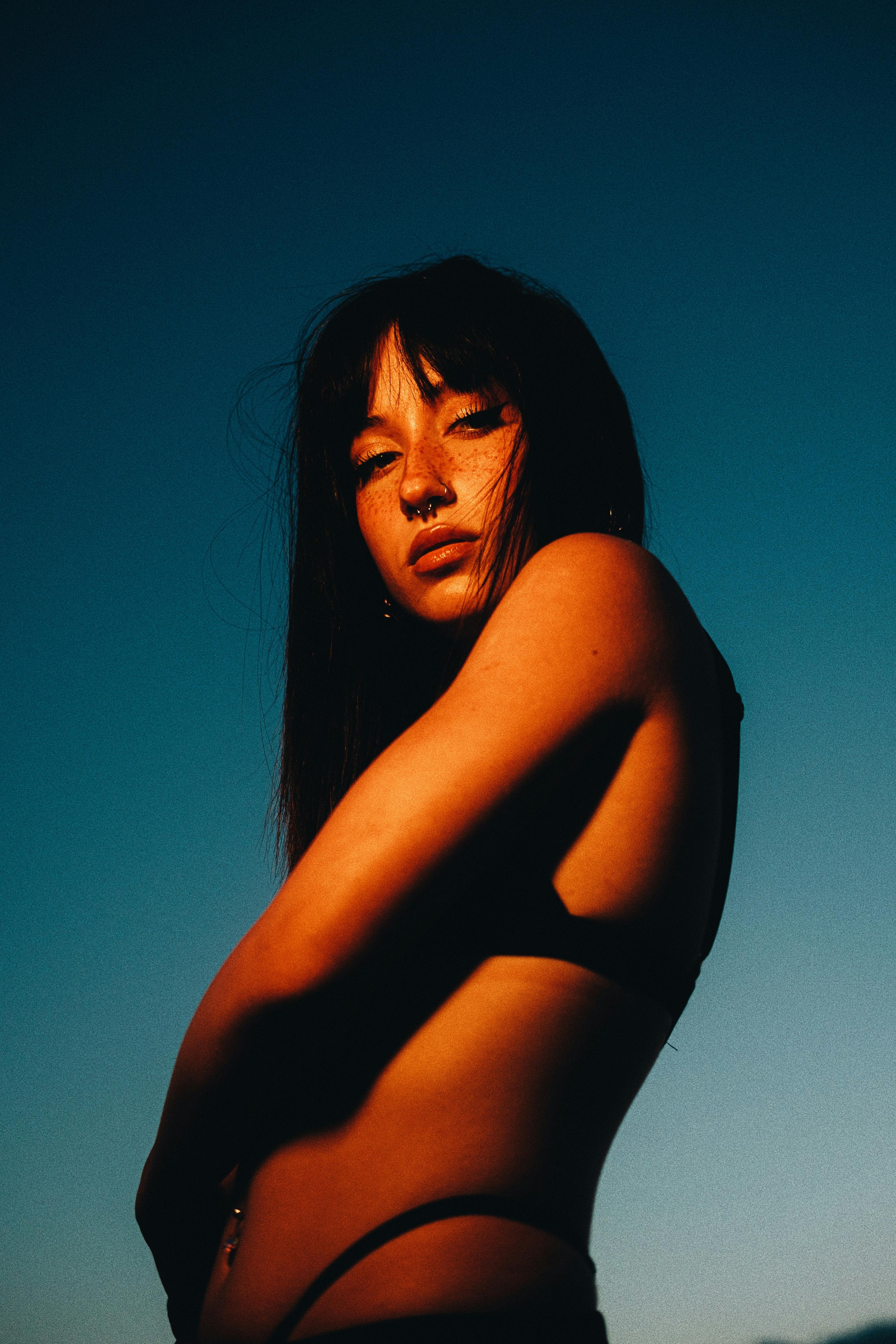 Young Woman in Bikini Posing on Blue Sky on Sunset · Free Stock Photo