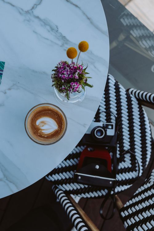 Free Elegant café table in Ankara with cappuccino, vintage camera, and floral decor enhancing its charm. Stock Photo