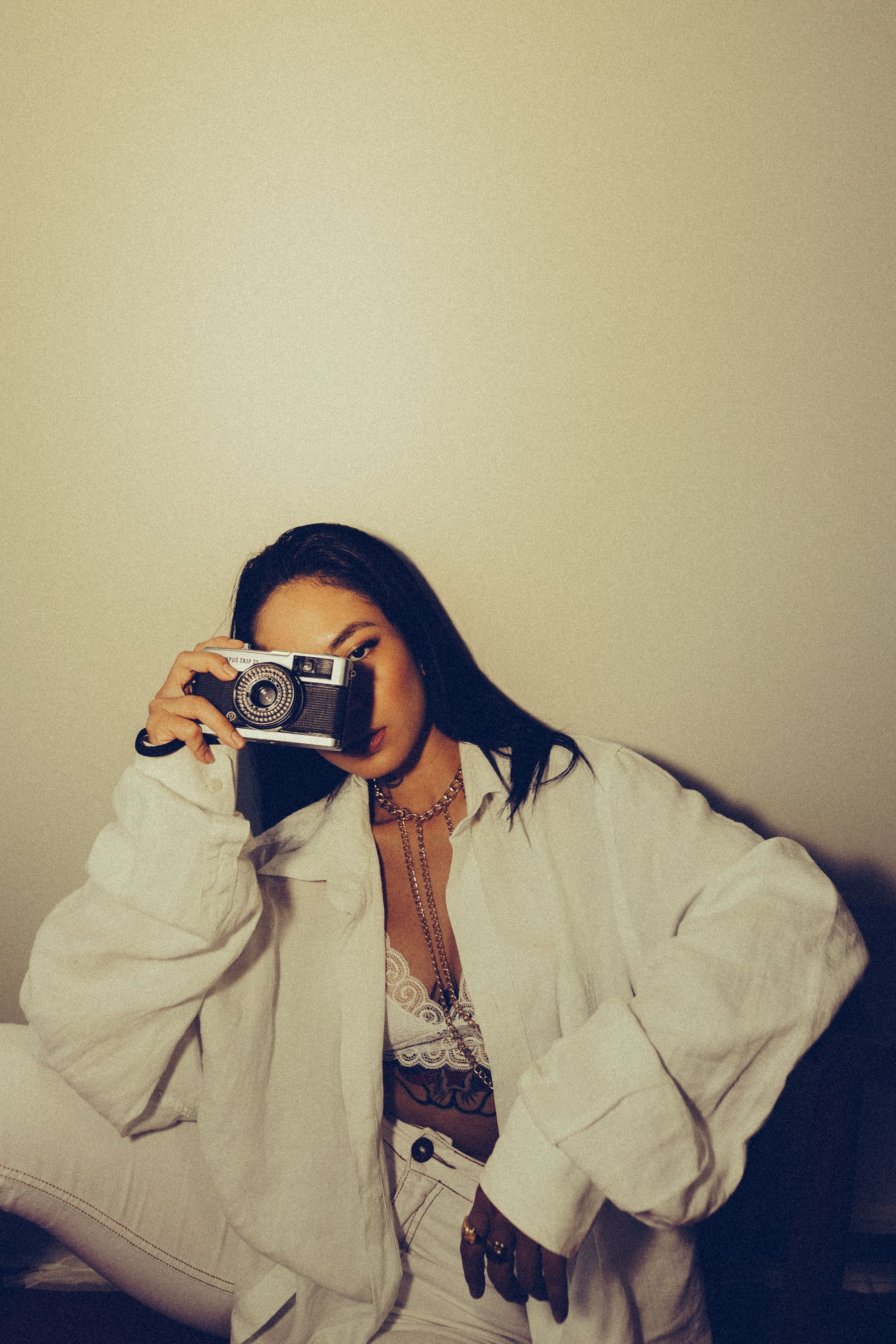Stylish woman in a vintage outfit with a camera, captured indoors with warm lighting.