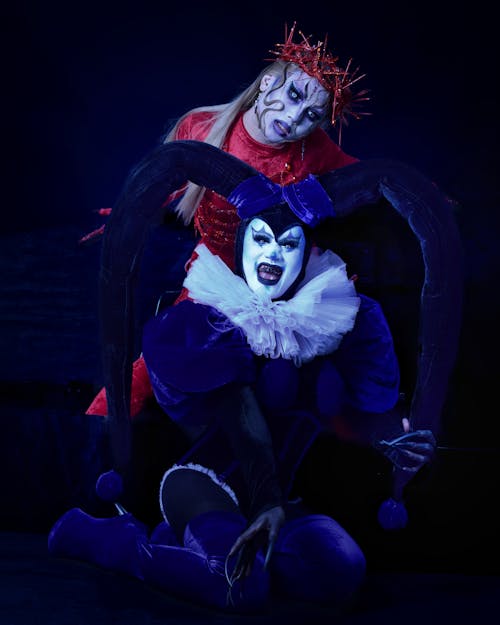 People in Eccentric Circus Costumes Posing on Black Background