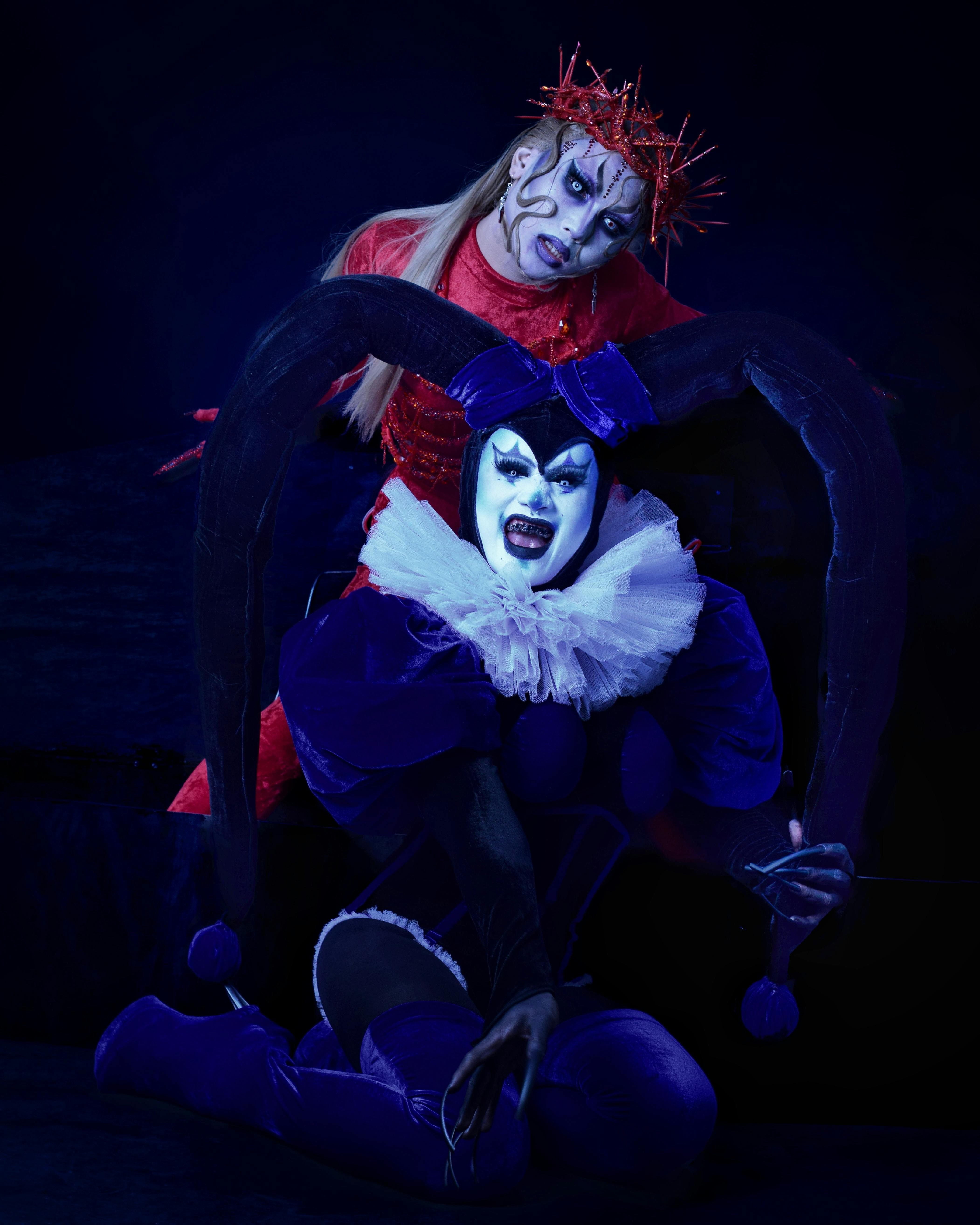 Free Two clowns in eccentric costumes pose dramatically against a dark background. Stock Photo