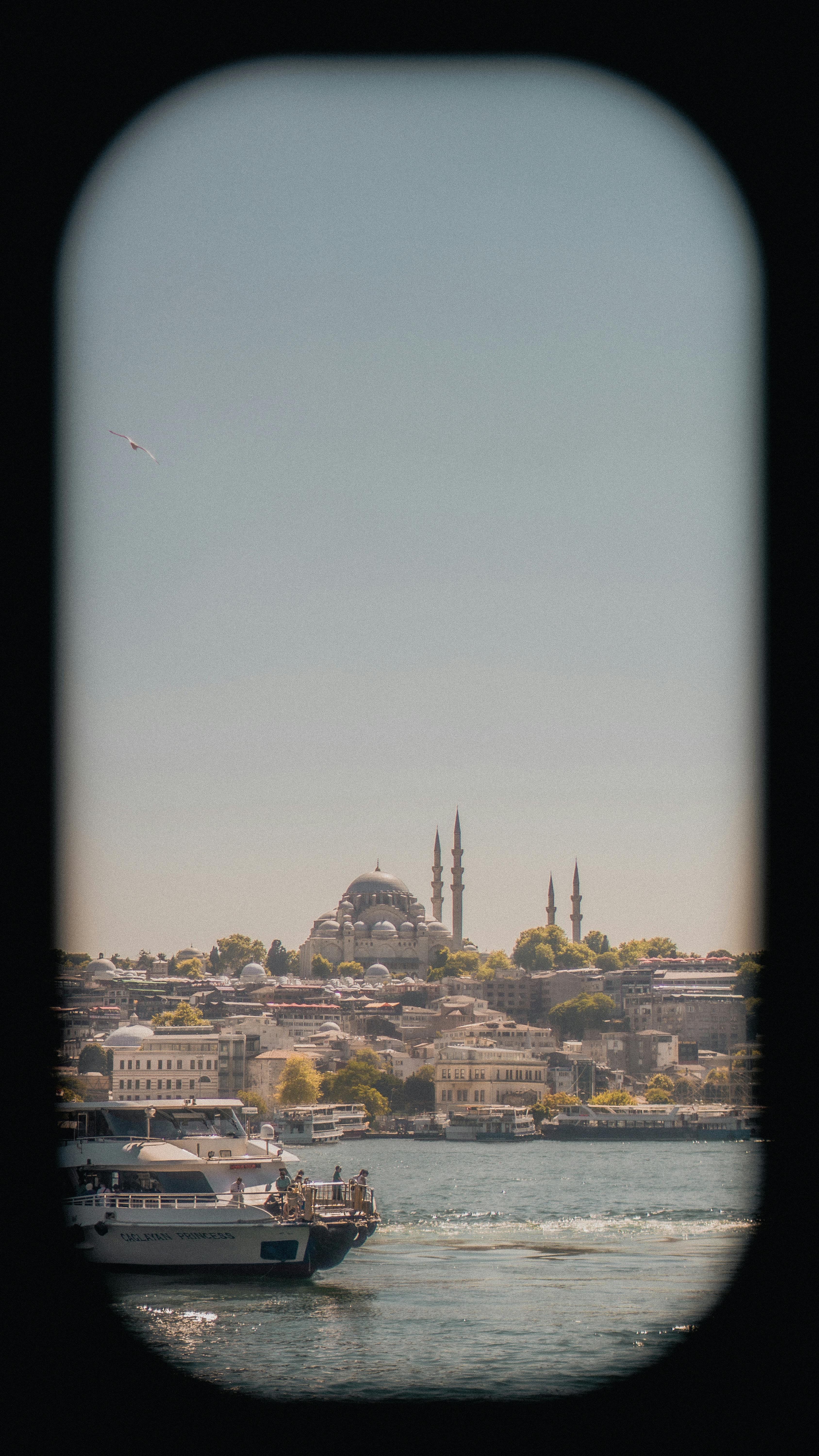 A picturesque view of Istanbul with a mosque seen through a boat window on a clear day.