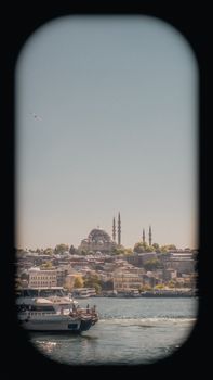 A picturesque view of Istanbul with a mosque seen through a boat window on a clear day.