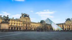 巴黎的卢浮宫博物馆，其标志性的玻璃金字塔在晴朗的蓝天映衬下显得格外引人注目