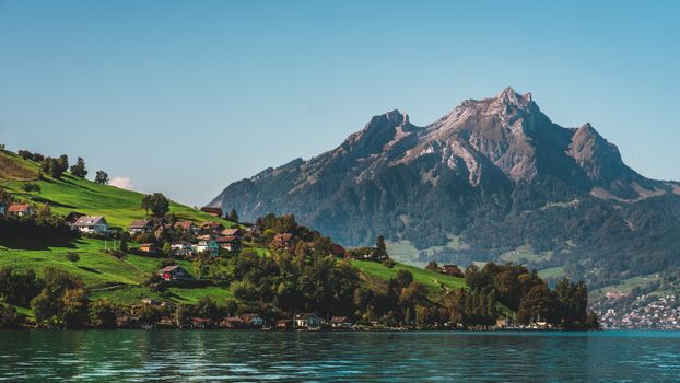 Picturesque view of Swiss village by a lake with majestic mountain backdrop.