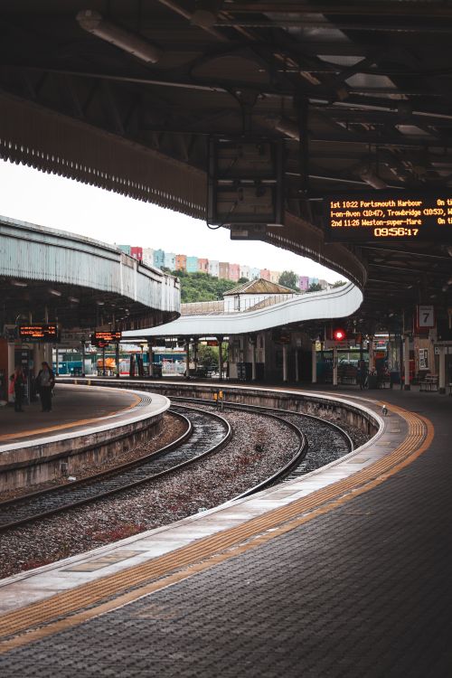 Free Curved train platforms at an urban station in England, featuring tracks and a digital display. Stock Photo