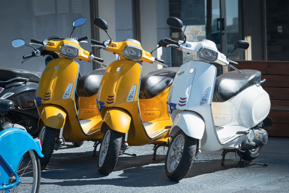 A vibrant display of yellow and white scooters parked on a city street, showcasing urban mobility.