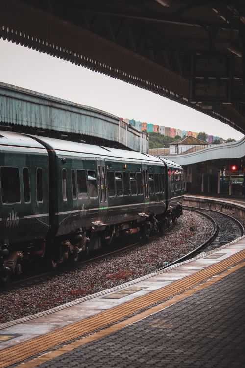 Free A sleek passenger train moves through an urban railway station with colorful buildings in the background. Stock Photo