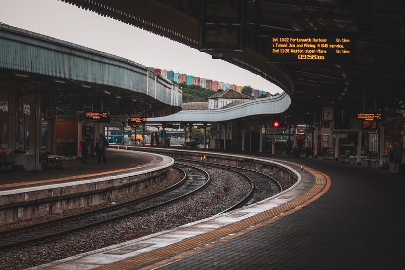 Urban train station with curved tracks and platform, featuring modern architecture.