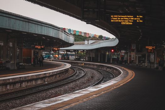Urban train station with curved tracks and platform, featuring modern architecture.