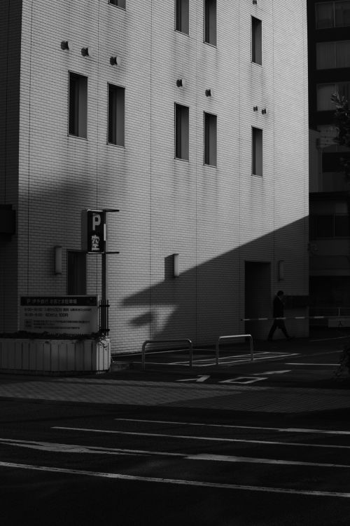Free Monochrome city street capturing strong shadows and architectural structure. Stock Photo