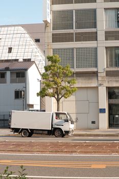 A white truck parked beside a modern building in a city setting, showcasing urban life.