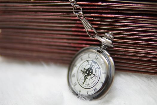 Elegant silver pocket watch with Roman numerals on a textured backdrop.