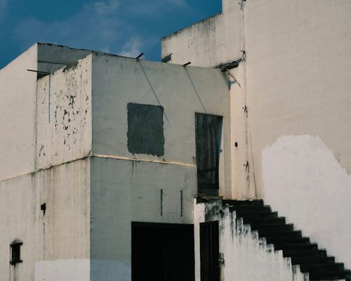 Free Abandoned building exterior with weathered walls and staircase under a clear blue sky. Stock Photo