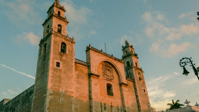 The grand facade of Mérida's iconic cathedral bathed in warm sunset light. — lounges at Merida Airport