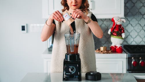 Free Womna Pouring Powder on the Blender Stock Photo