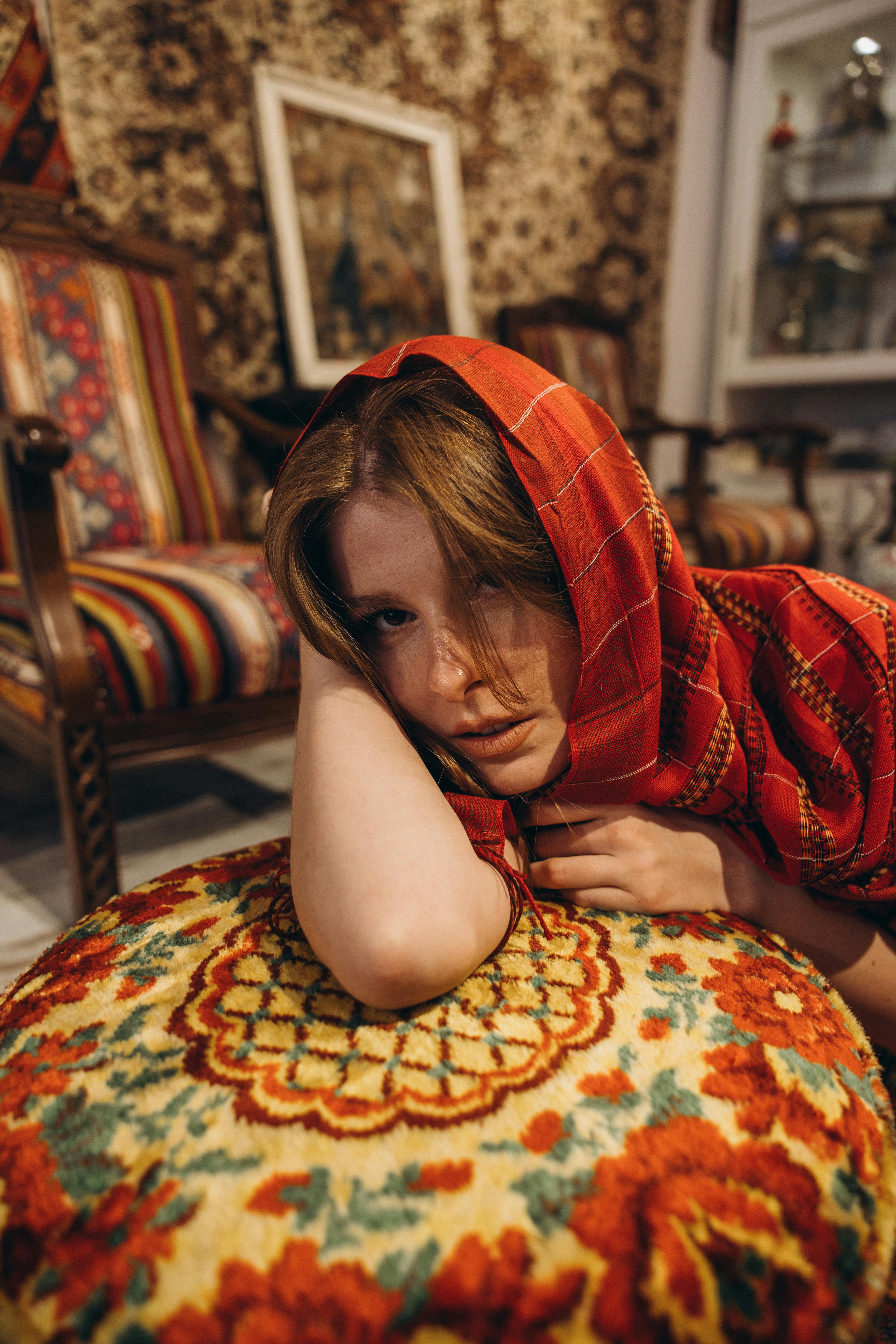 a woman in a red scarf sitting on a cushion