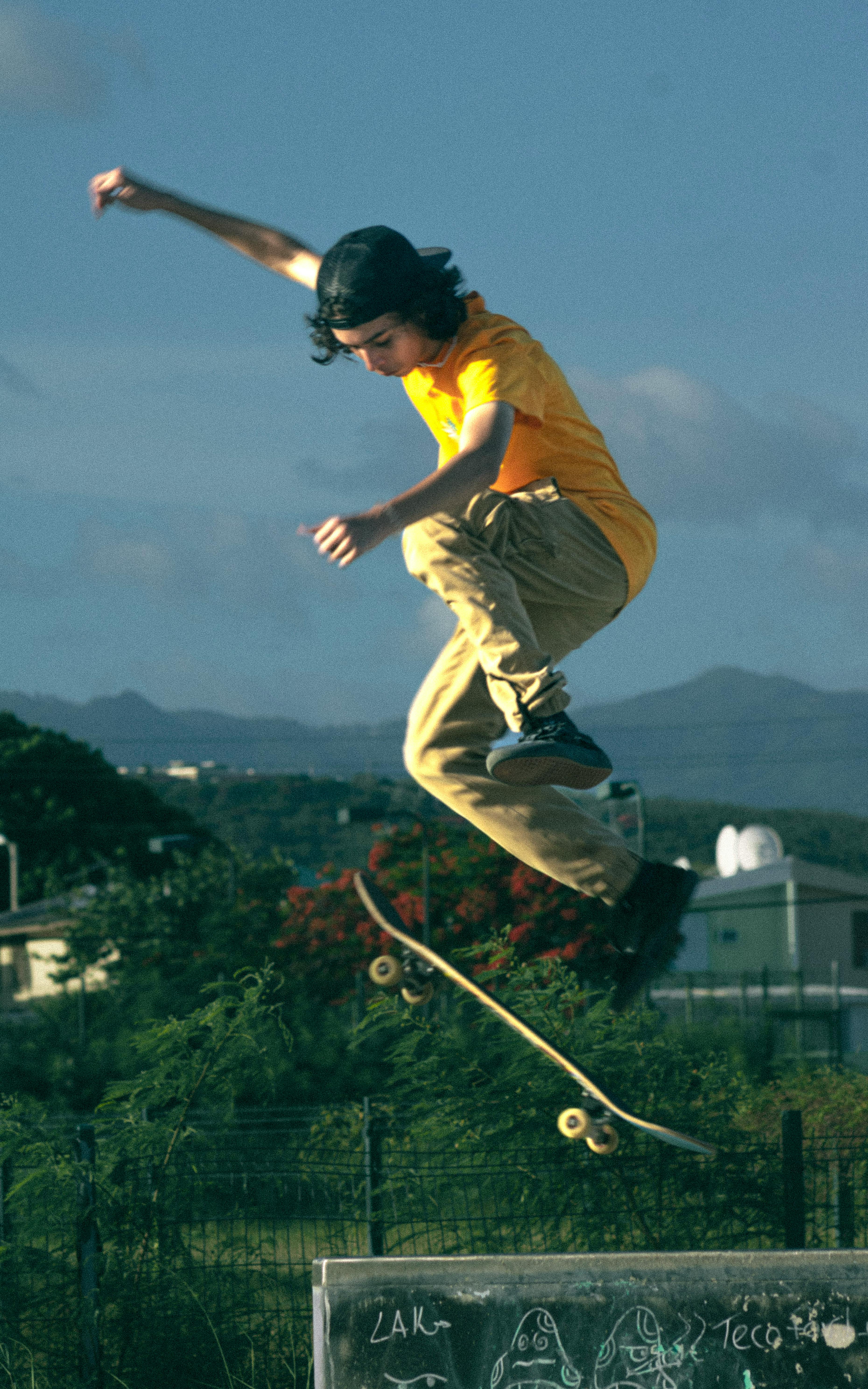 Dynamic shot of a young skateboarder executing an ollie in an outdoor urban setting.