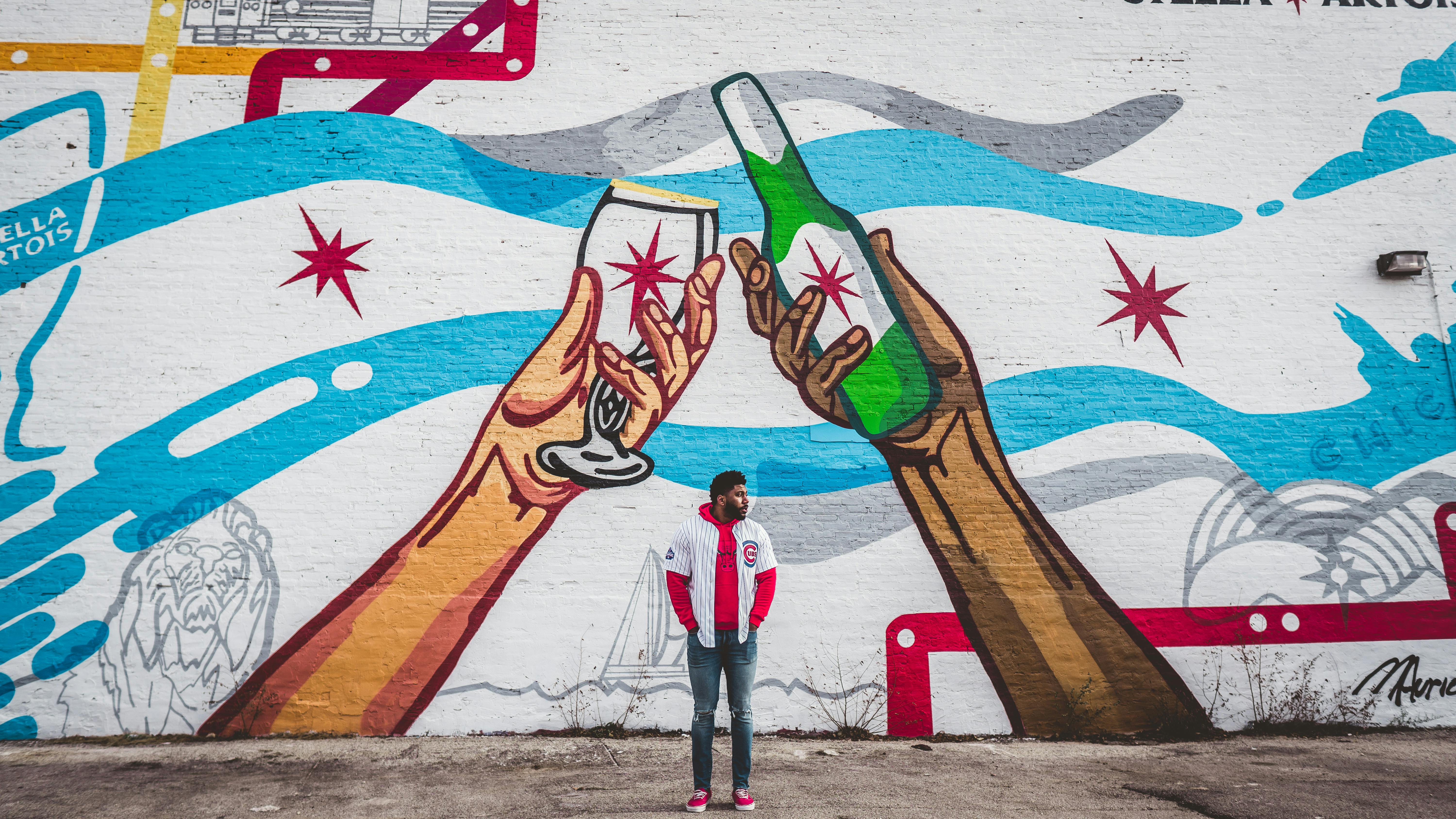 Vibrant street art in Chicago depicting hands holding drinks, observed by a young adult.