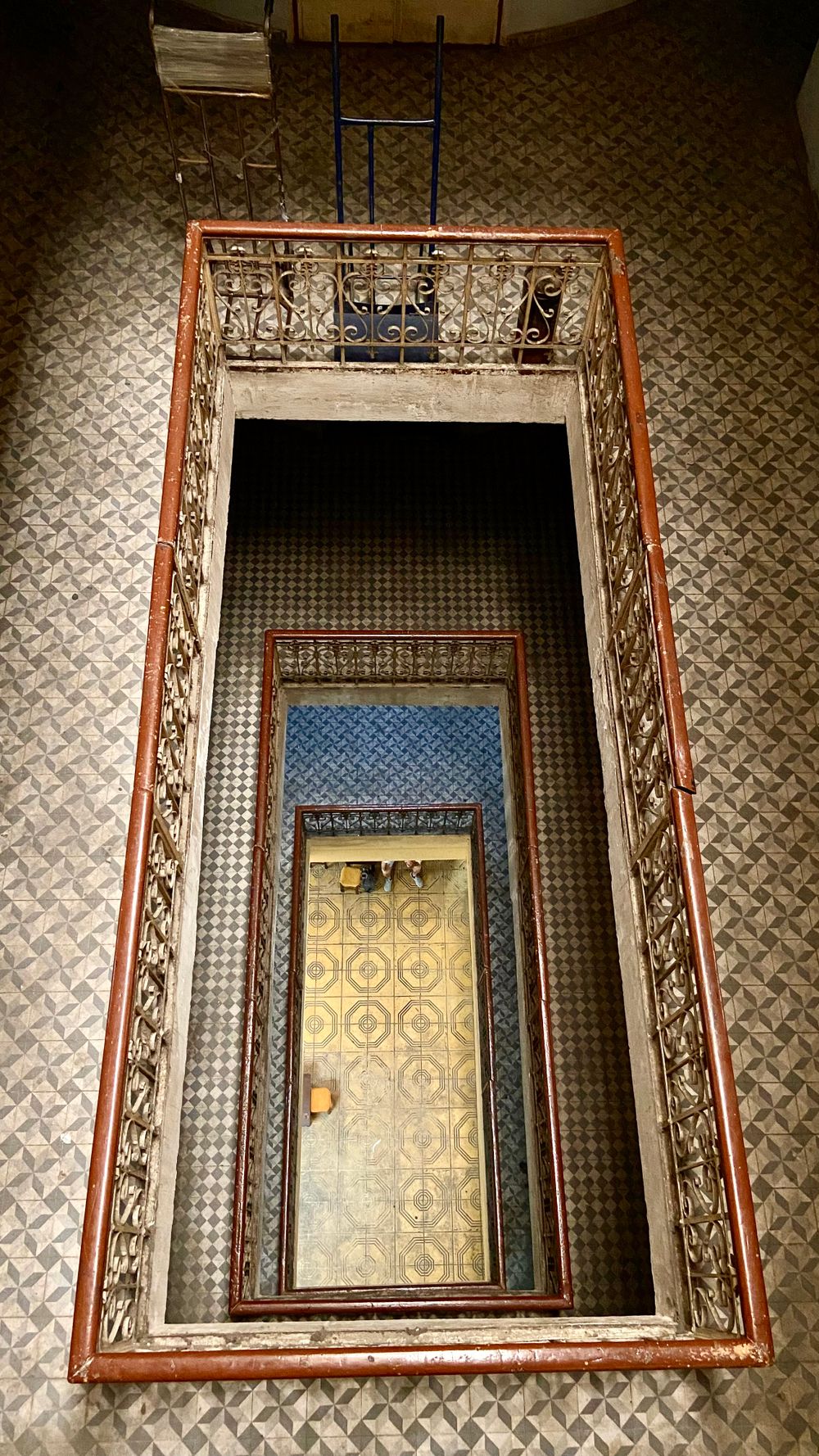 Cage d’escalier d’un immeuble ancien, rampe en fer forgé, vue plongeante