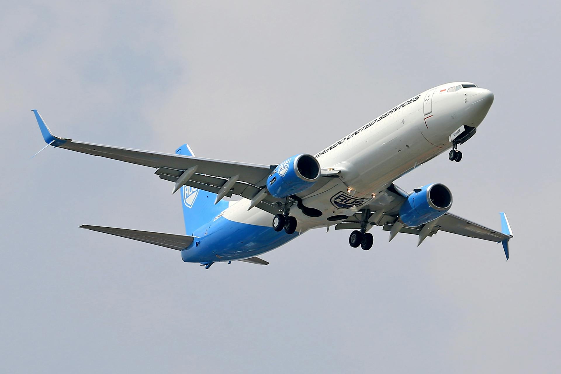 A Boeing 737 cargo aircraft flying with landing gear retracted against a clear sky.