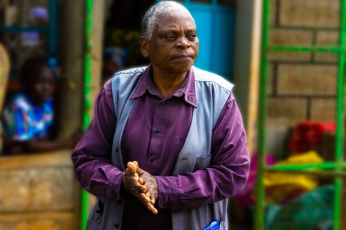 Free Senior African American man wearing a purple shirt and vest, outdoors in an urban setting. Stock Photo
