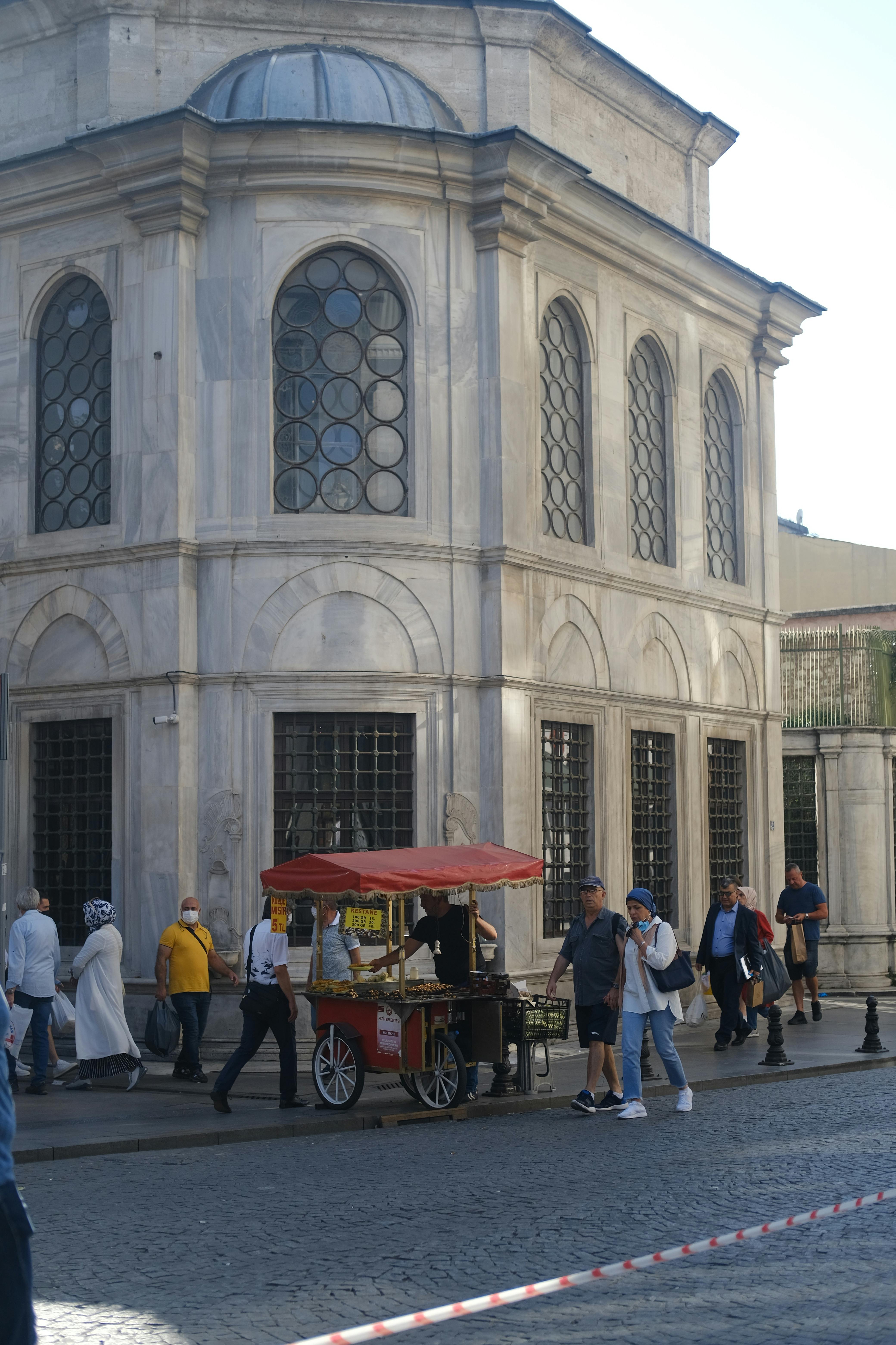 People walking by a street vendor near the Tomb of Abdul Hamid I in Istanbul, Türkiye.