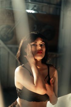 Elegant woman posing indoors with dramatic lighting and shadows, highlighting her beauty.