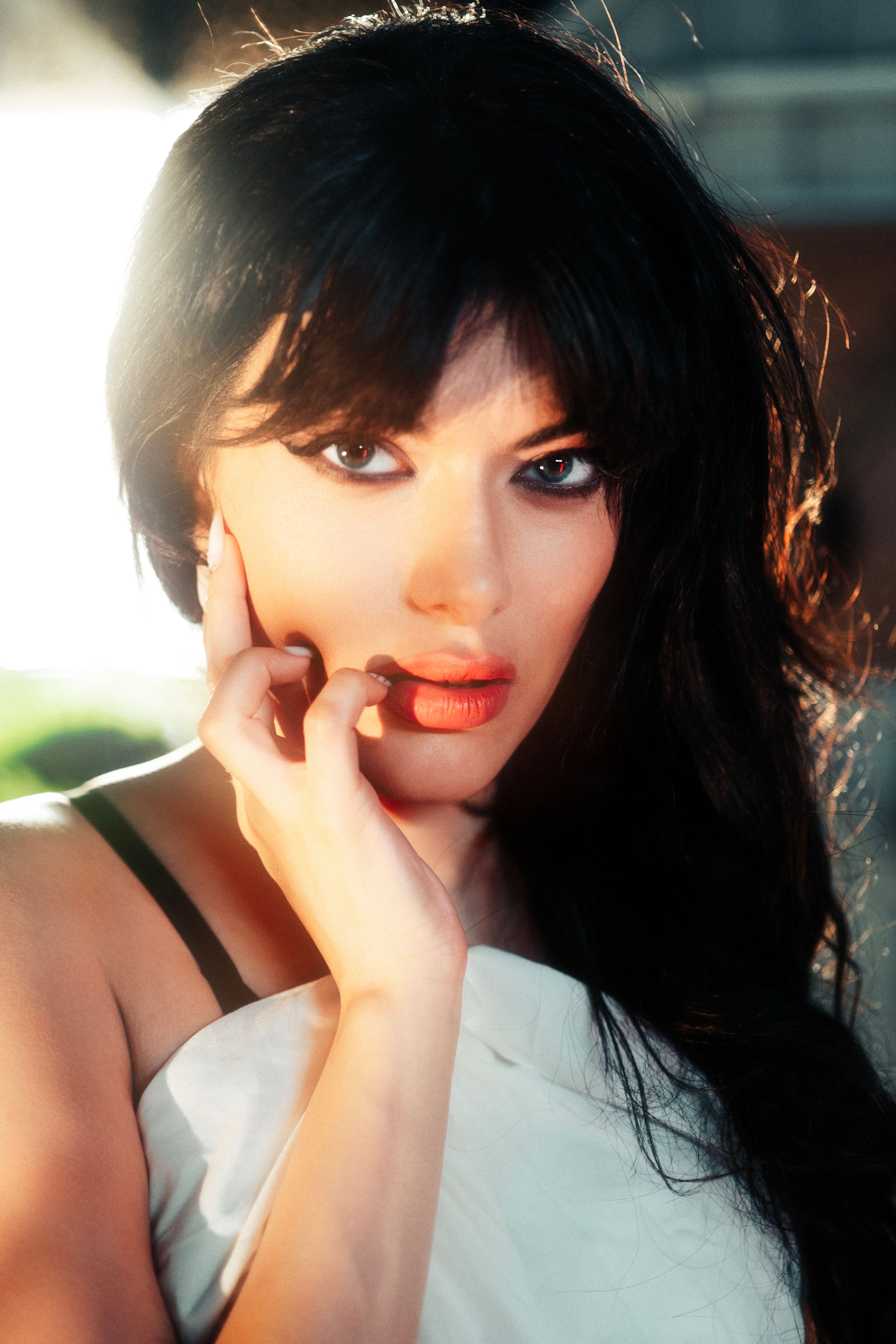 Striking portrait of a young woman with bold makeup and dark hair, looking directly at the camera.
