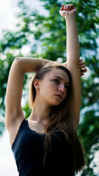 Portrait of a woman striking a pose with blurred greenery background.