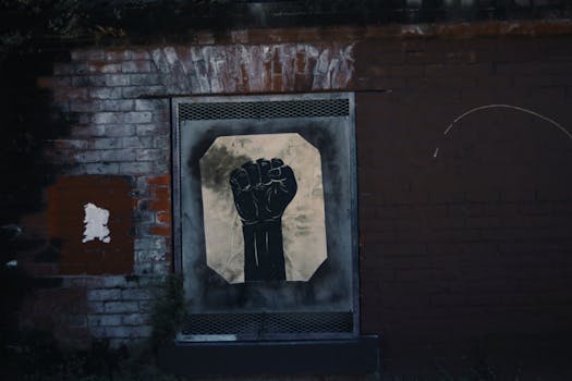 在饱经风霜的砖墙上，画着一只黑色的拳头，展现出强大的街头艺术
