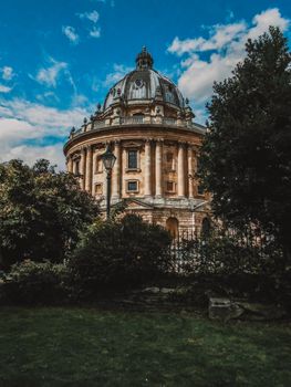 Photograph of the iconic Radcliffe Camera in Oxford, England surrounded by lush greenery.