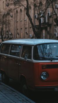 Classic red van parked on a tree-lined city street, evoking a vintage urban atmosphere.