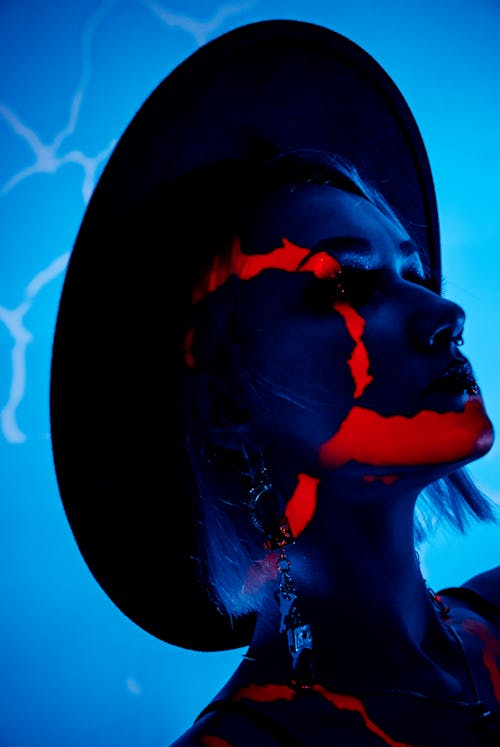 Model in a Wide Brimmed Hat in Blue Lighting with Red Light Patterns