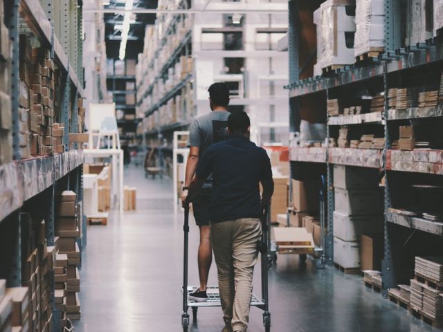 Workers moving a loaded trolley through a bulk storage warehouse