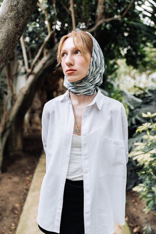 Model in Blue Headscarf and White Blouse Admiring the Garden