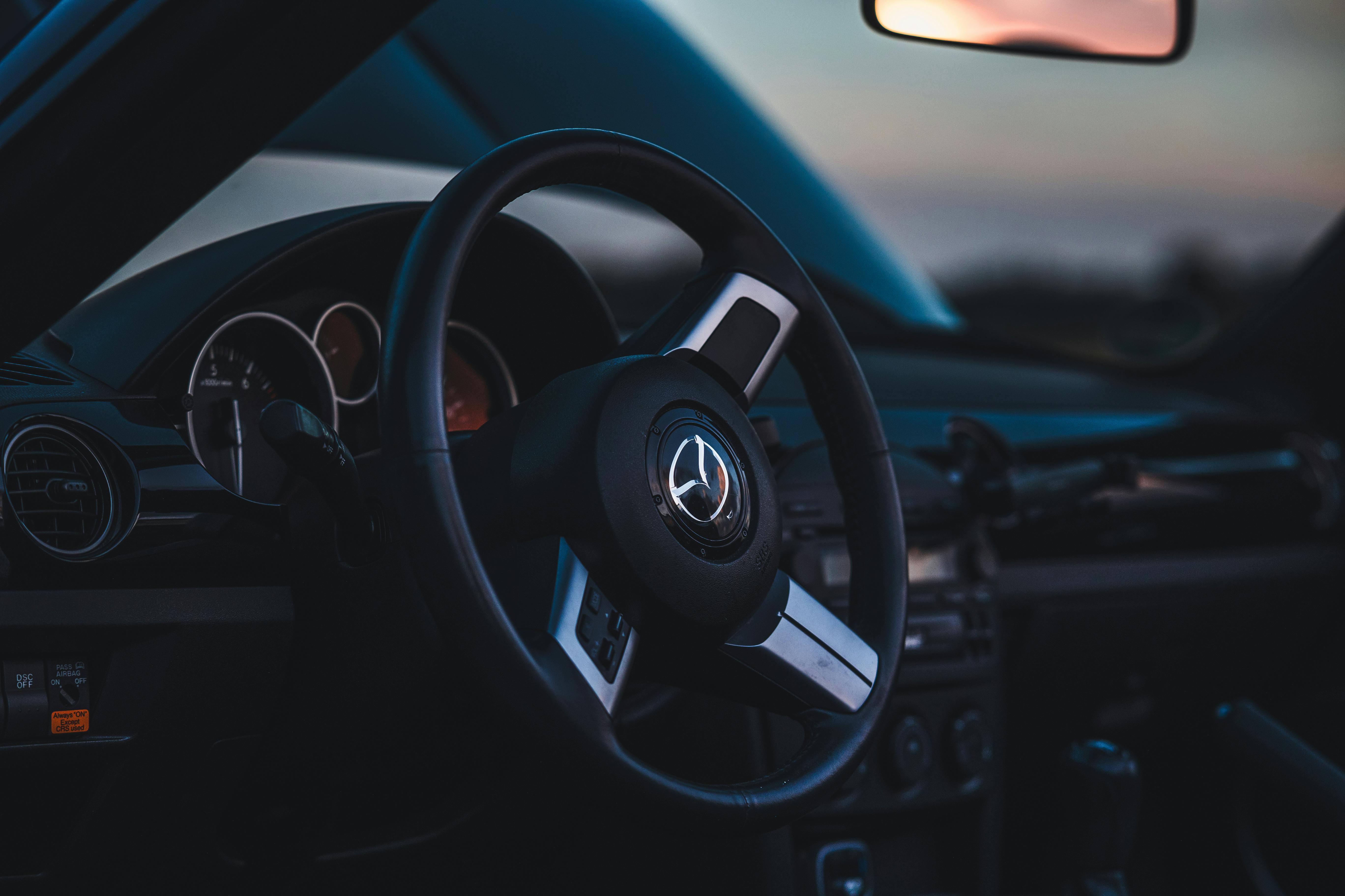 Free Close-up of a modern car's steering wheel and dashboard in low light. Stock Photo