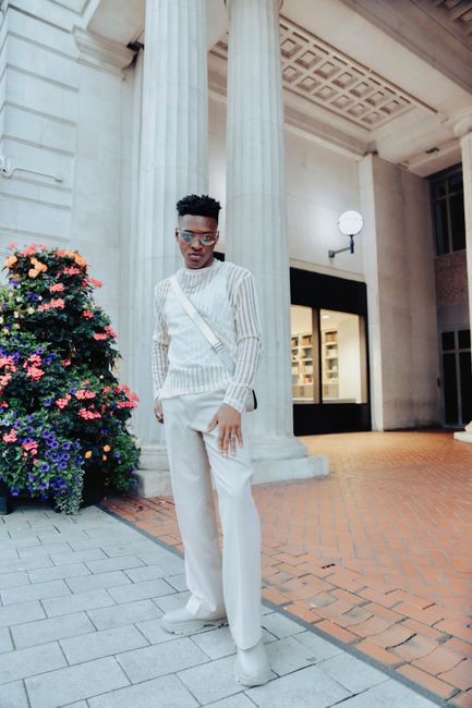 Fashionable man poses in a chic urban setting with classic architectural columns.