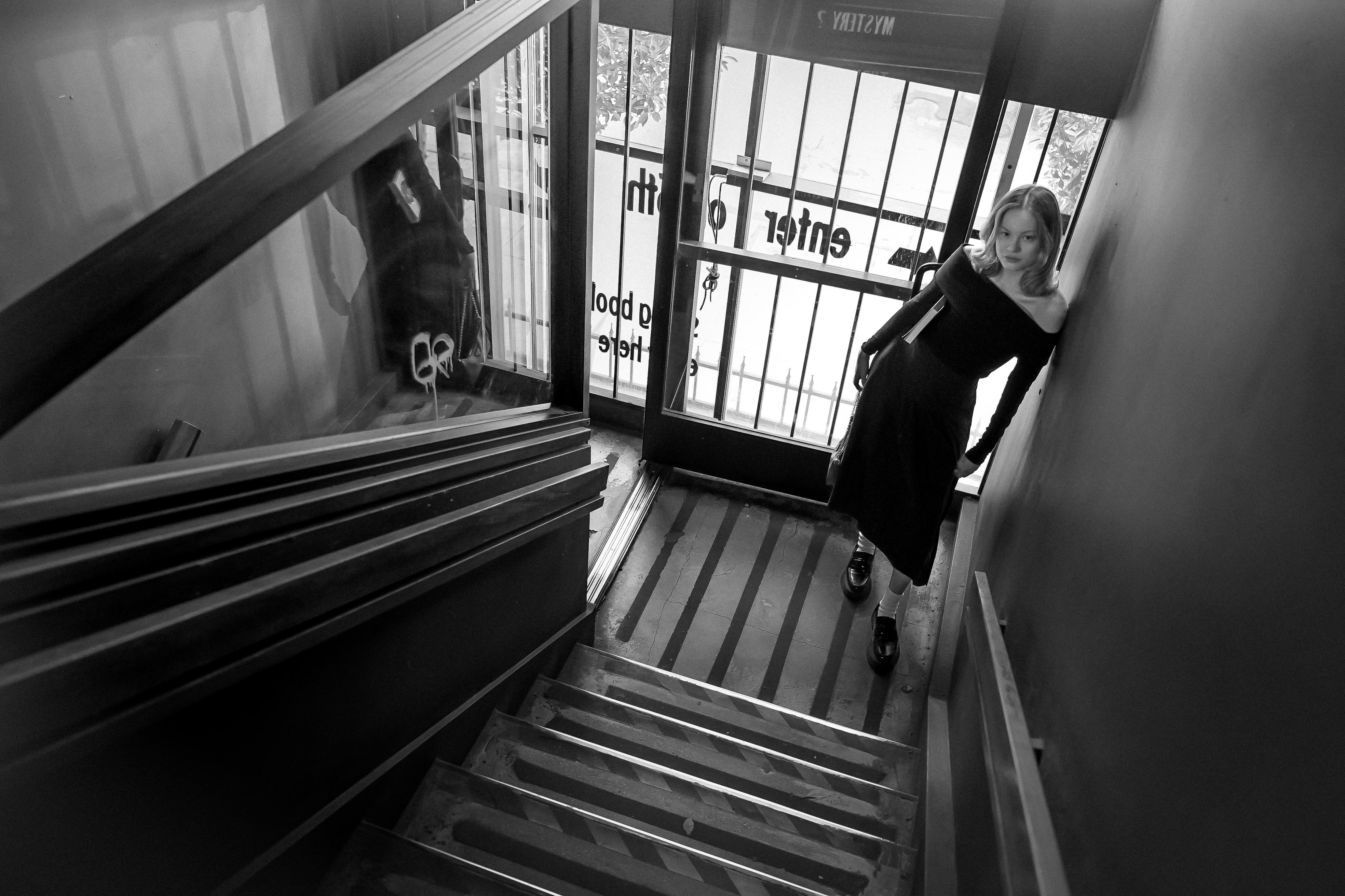 a woman is walking down the stairs in a black and white photo