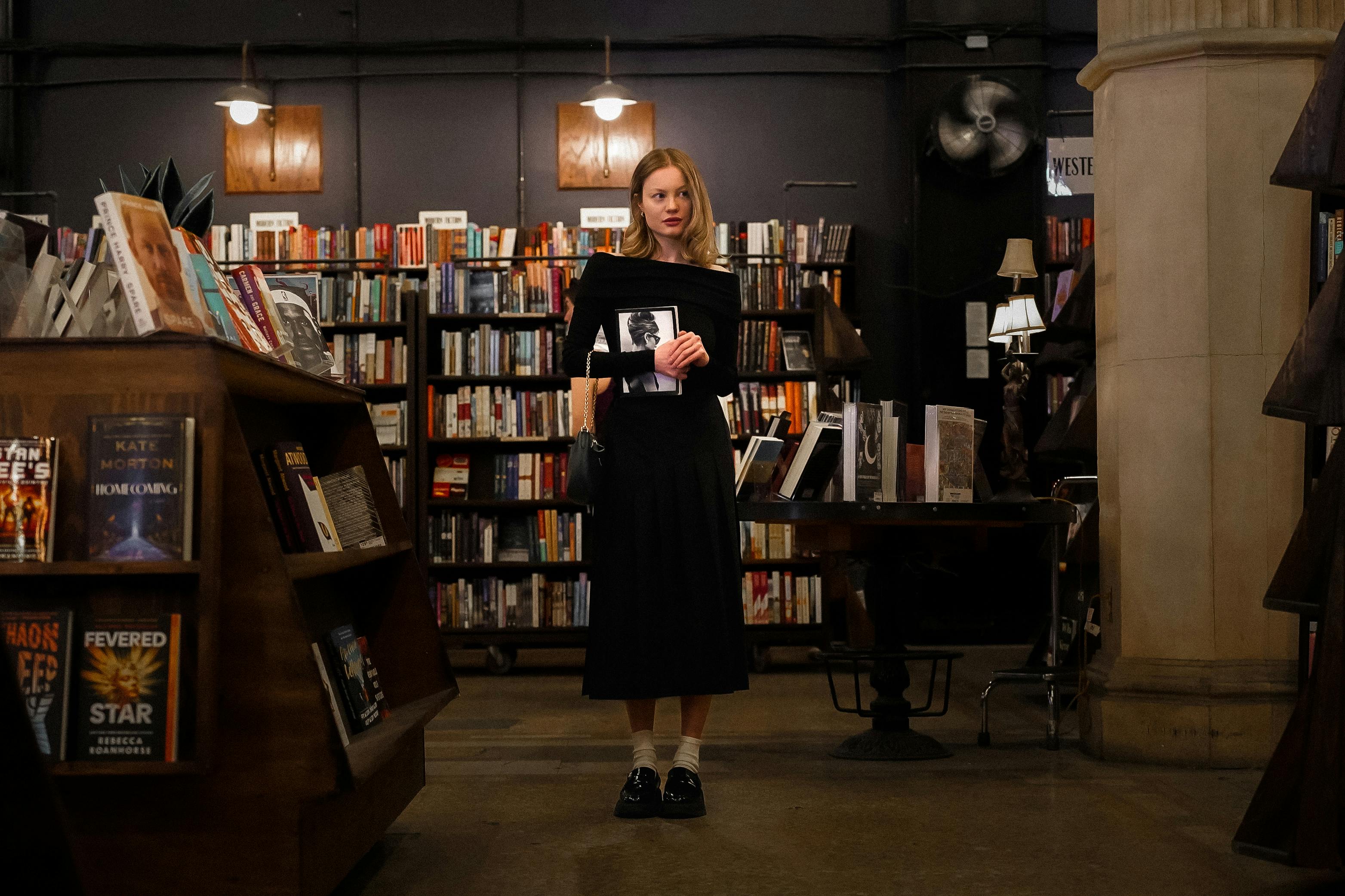 a woman standing in a bookstore holding a book