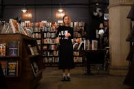 A woman standing in a bookstore holding a book