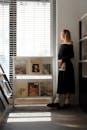 A woman standing in front of a window with books