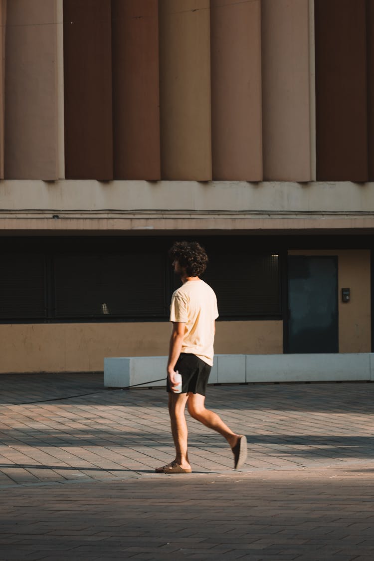 Young Man Walking On City Street On Sunset