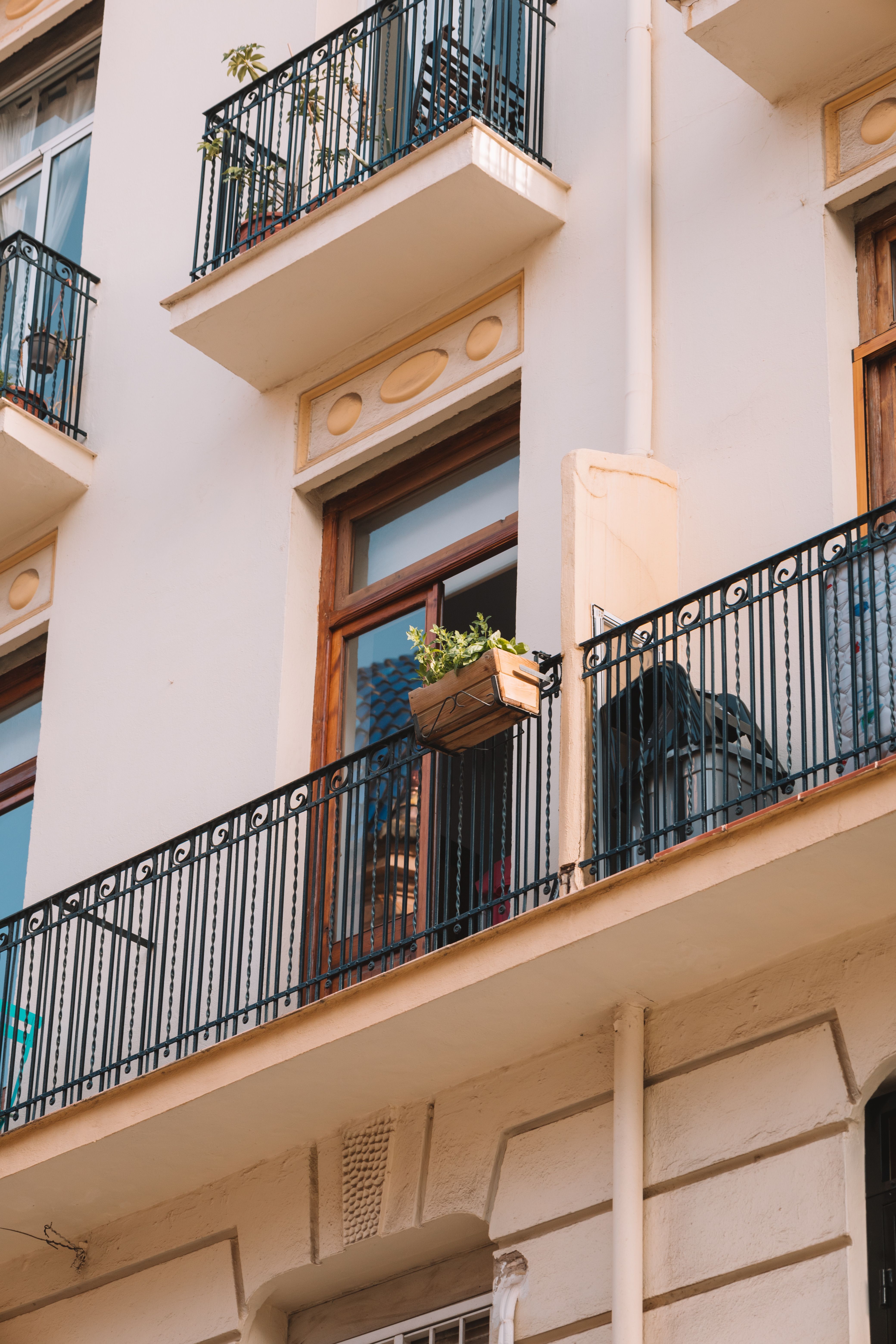 Clamp-on planters attached to the metal railing of a small apartment patio, holding small flowering plants